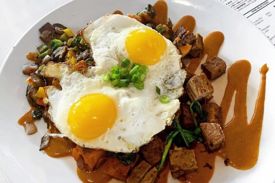 SMOKED BRISKET HASH AND EGGS* hickory smoked beef brisket, BBQ house potatoes, grilled onions, roasted peppers, four-cheese blend and red chili ranchero sauce, topped with two eggs your way and served with cornbread