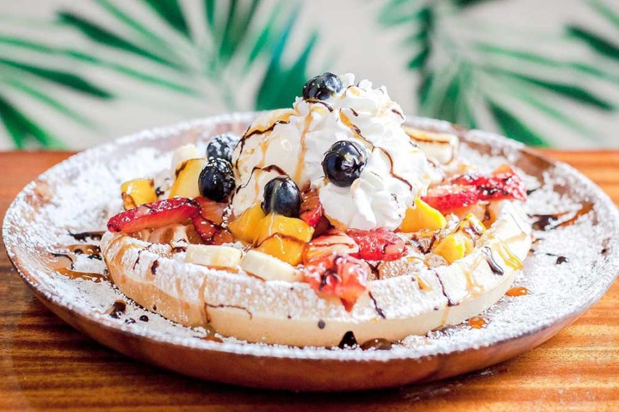 waffle topped with powdered sugar, fresh fruits, and whip cream from le crepe cafe in honolulu, hawaii