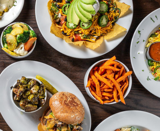 a variety of dishes from chicago diner including fully loaded nachos, a burger with a side of grilled brussel sprouts, and sweet potato fries