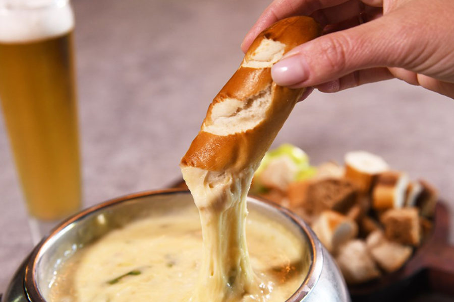 fresh pretzel being dipped in cheese at the melting pot in san diego