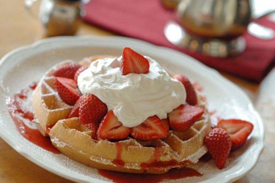 waffle topped with whip cream and fresh strawberries from the original pancake house in denver