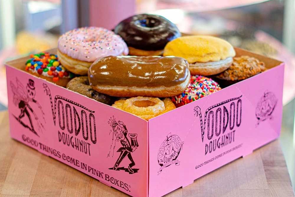 A box of Voodoo Doughnuts filled with doughnuts of different sizes, shapes, and colors