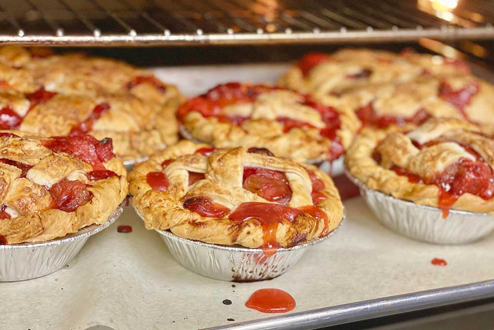 Several cherry pies on a sheet tray