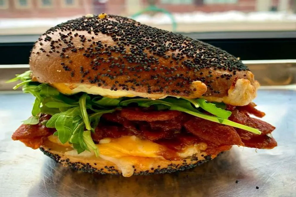 Bacon, egg, cheese, and arugula on a poppy seed bagel