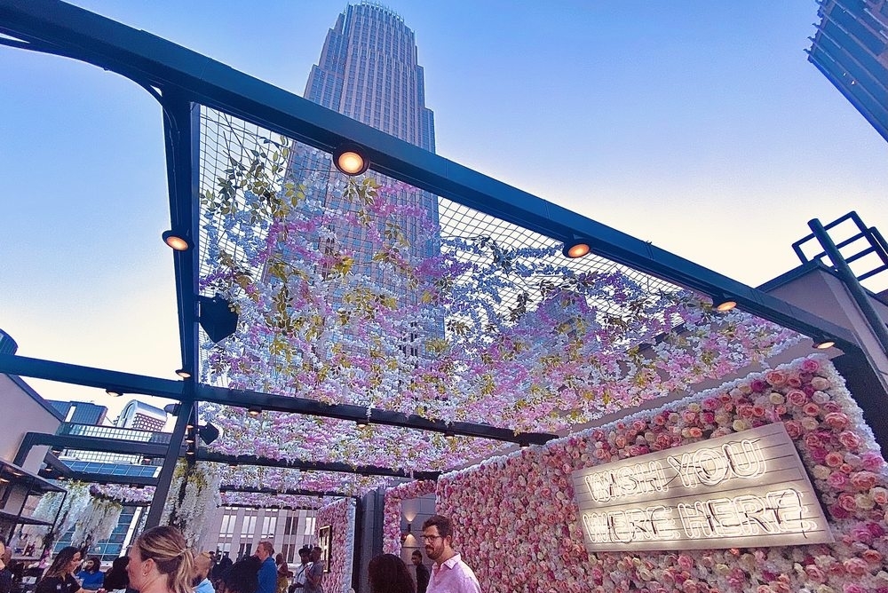 rooftop dining area with floral decor and a view of the charlotte skyline at novelty rooftop
