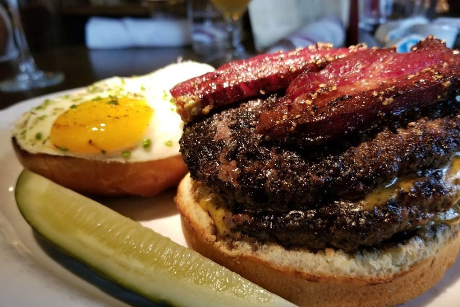 burger with two meat patties, thick cut bacon, and a poached egg from au cheval in chicago