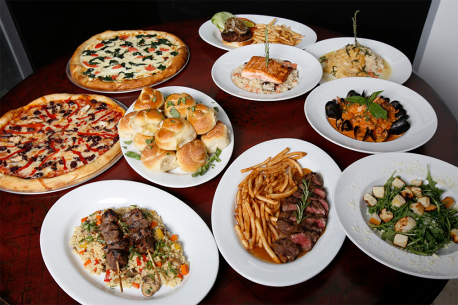 an assortment of dishes including pizza, fried rice, skewers, steak, salmon, bread rolls, fries, ocean mussels, and caesar salad from crust restaurant in miami