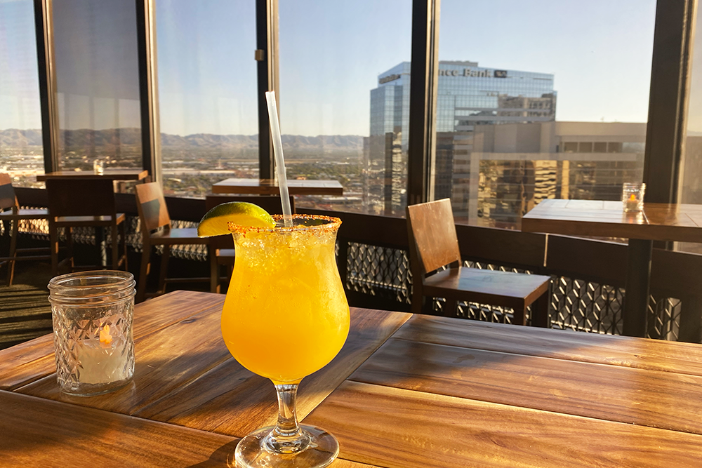 Mango margarita on table overlooking city at Compass Arizona Grill Rooftop Restaurant in Phoenix, Arizona