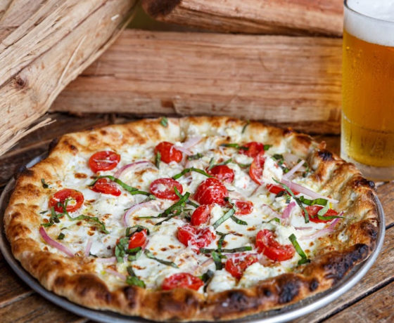 pizza with onion and tomato with a cold beer from crust wood fired pizza and bailey's oyster bar in charleston