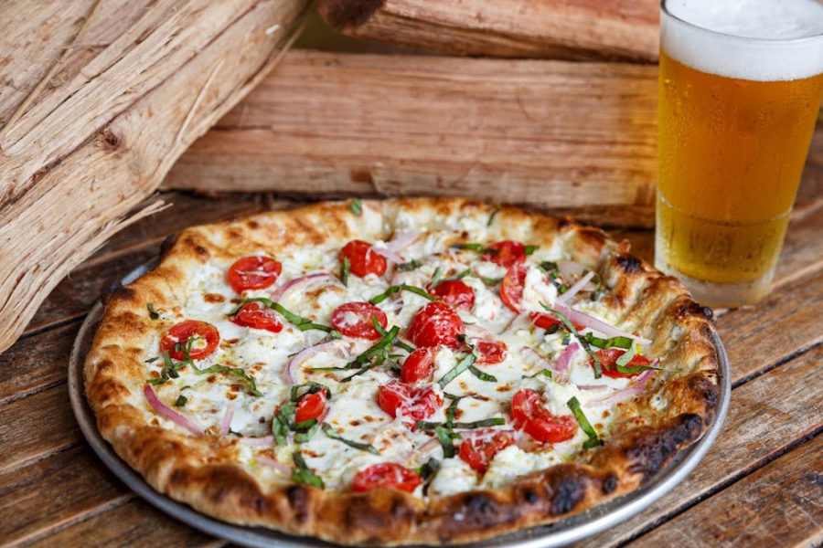 pizza with onion and tomato with a cold beer from crust wood fired pizza and bailey's oyster bar in charleston