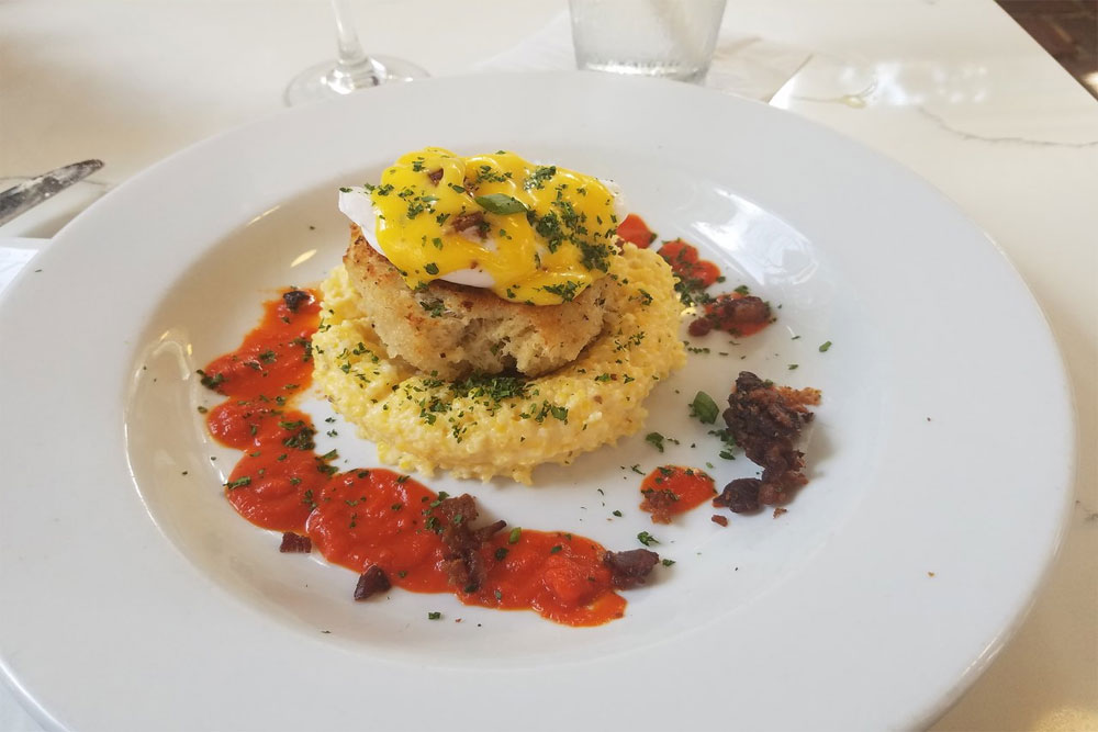 Crab cake on a white dish surrounded by garnishes