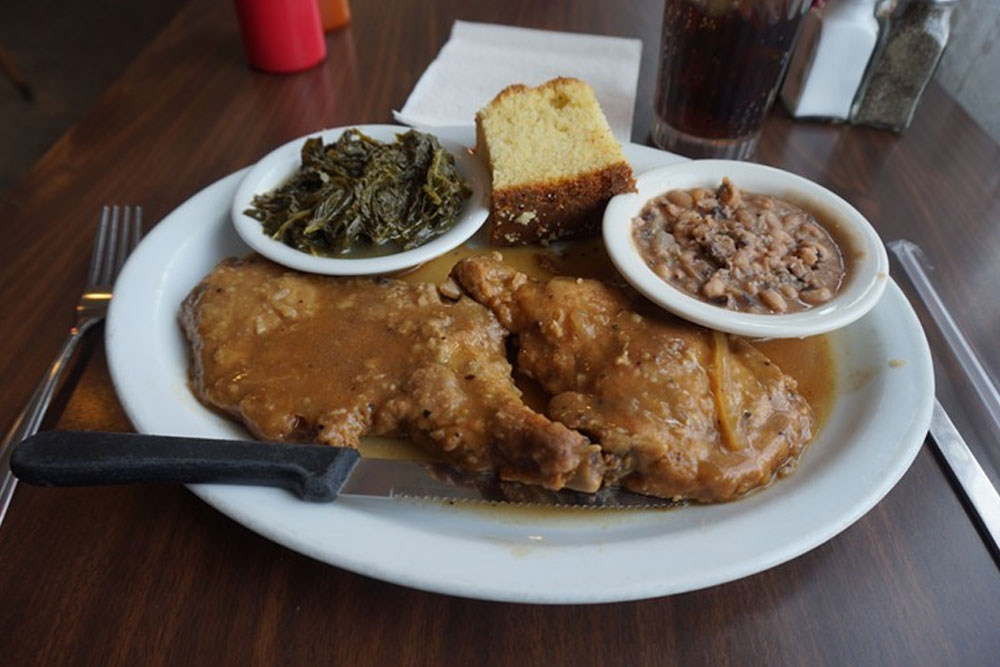 pork chops smothered in gravy with sides of collard greens, baked beans, and cornbread from Welton St. Cafe in Denver