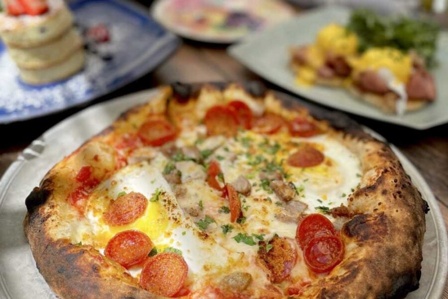 The Hangover Pizza is loaded with sausage, pepperoni, bacon, sunnyside-up eggs & 3 cheese gratin from Source Restaurant