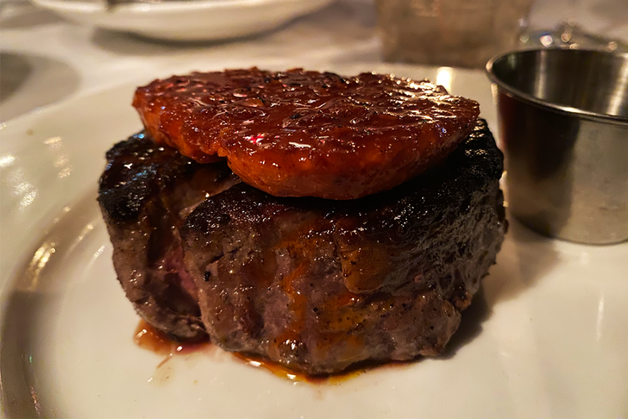 A dim image of a steak filet with a red disc of chili crisp butter on top
