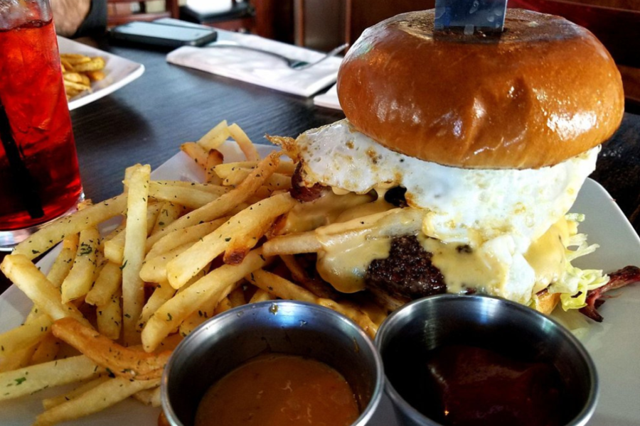 Dirty Burger topped with beer cheese sauce, pulled pork, fries and a fried egg from pitchers sports bar in San Diego