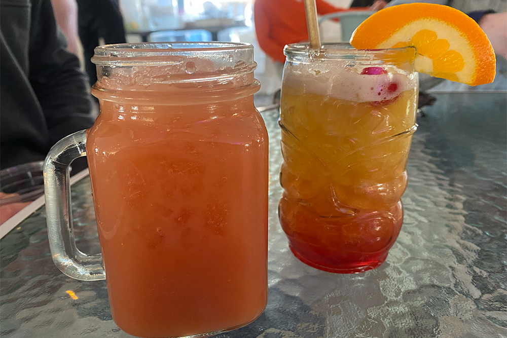 Two cocktails, one with an orange slice on the rim