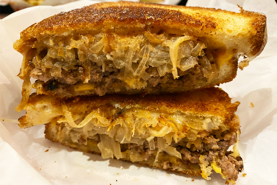 Patty melt with onions and cheese sliced in half and placed in one stack
