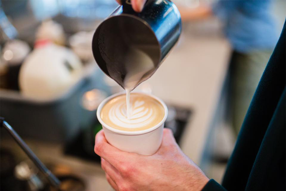 Steamed milk being poured on top of a latte