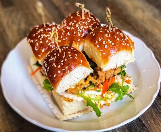 Four oyster sliders on a white plate