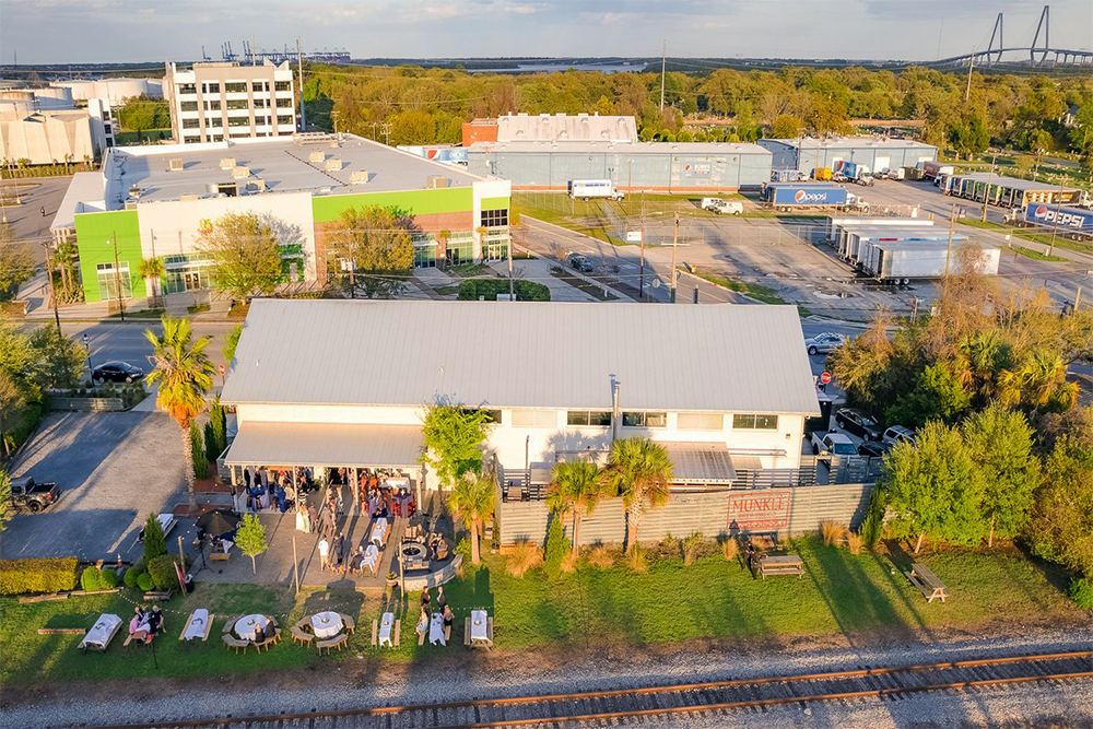 Drone shot of Munkle Brewing with people sitting on the patio and train tracks in the foreground