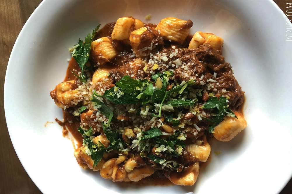Gnocchi with a short rib ragu, cheese, and greens on top
