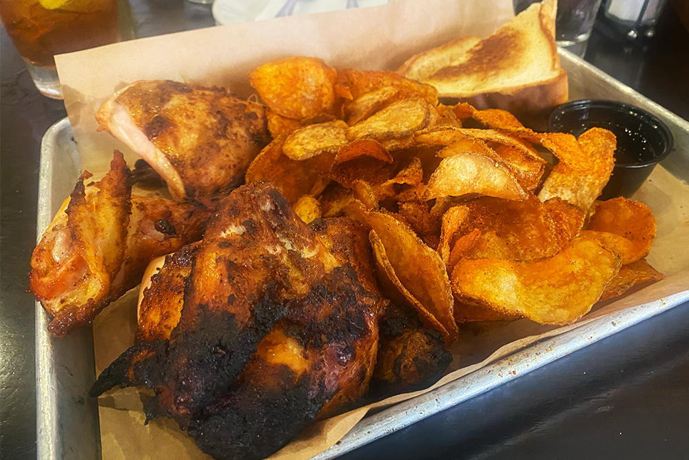 Half chicken cut into pieces with a side order of seasoned potato chips