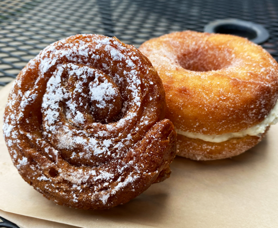 Two pastries on a brown paper bag on a black table