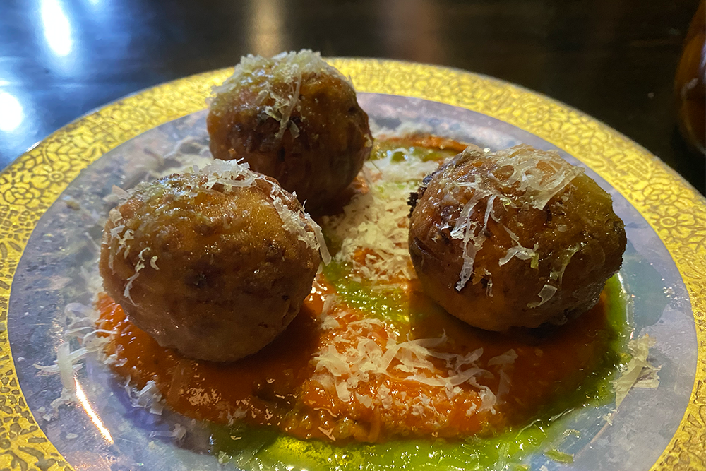 Fried balls on a red and green sauce
